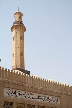 a tall tower with a clock on it's side next to a sign that says,