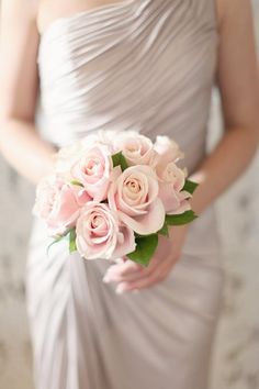 a bride holding a bouquet of pink roses