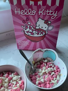 two bowls filled with pink and white cereal next to a hello kitty box on a counter