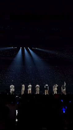 a group of people standing on top of a stage in front of a crowd at night