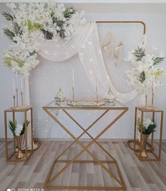 a table with flowers and candles on it in front of a wall decorated with lights