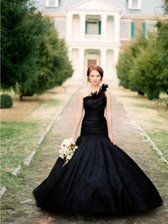 a woman in a black dress is standing outside