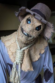 a creepy scarecrow with blue eyes wearing a hat and scarf