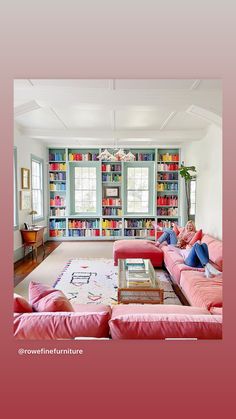 a living room filled with pink couches and bookshelves full of colorful books