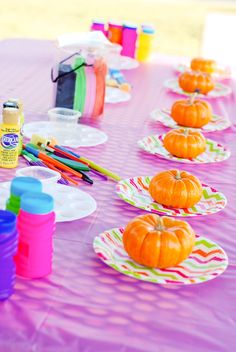 there is a purple table with pumpkins on it and paint bottles in the background