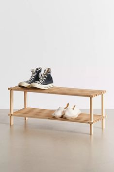 two pairs of shoes are sitting on a wooden bench with white walls in the background