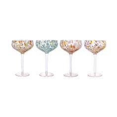 four wine glasses sitting next to each other on top of a white surface with different designs