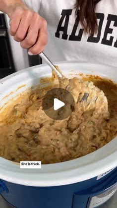 a woman is mixing some food in the crock pot with a ladle and spoon