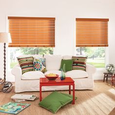 a living room filled with furniture and windows covered in shades of orange, green, and white