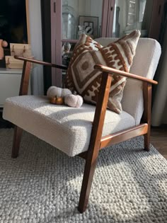 a chair with pillows on it in front of a mirror