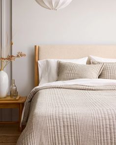 a bed with white sheets and pillows in a bedroom