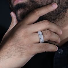 a man wearing a wedding band with a diamond ring on his left hand, looking at the camera