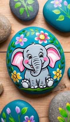 an elephant painted on rocks with flowers and leaves around it, surrounded by other rocks