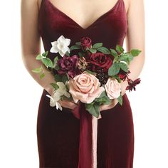 a woman in a red dress holding a bouquet of roses and other flowers on her arm