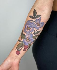 a woman's arm with flowers and berries on it