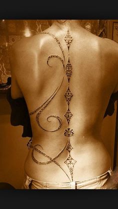 the back of a woman's body with an intricate tattoo on her lower back