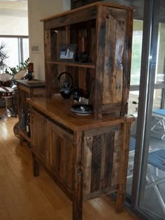 a wooden cabinet sitting in the middle of a living room next to a glass door