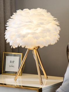 a lamp that is sitting on top of a table next to a photo frame and pillow