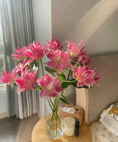 pink flowers are in a vase on a small table