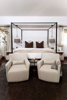 a bedroom with four poster bed, two chairs and a coffee table in the middle