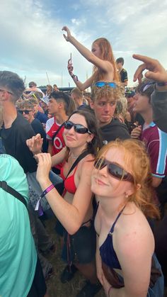 a group of people standing next to each other at a music festival in the sun