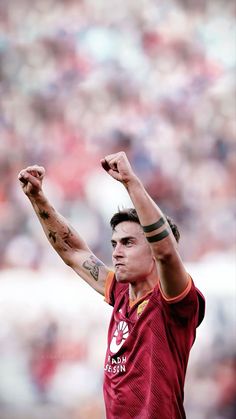 a man with tattoos on his arm raising his arms in the air at a soccer game