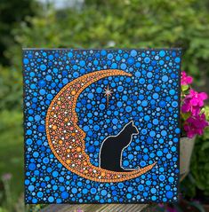 a black cat sitting on top of a blue moon with stars and bubbles painted on it