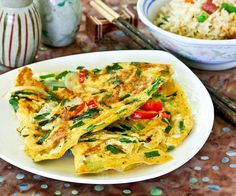 an omelet with vegetables and rice is on a plate next to a bowl