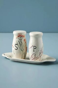 two salt and pepper shakers sitting on a plate with the word s p painted on them