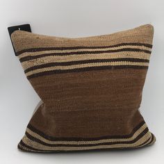 a brown and black striped pillow sitting on top of a white table