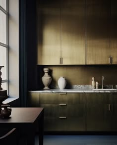 a kitchen with wooden cabinets and marble counter tops, along with vases on the table