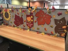 an office cubicle decorated with fall leaves and owl magnets on the bulletin board