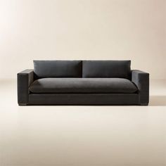 a black couch sitting on top of a floor next to a white wall with a light colored background