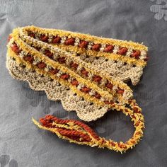 two crocheted bags sitting on top of a gray cloth covered in yellow and red yarn