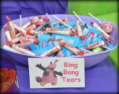 a bowl full of candy sticks with a sign on it that says bing bong tears