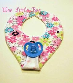 a baby bib with flowers on it and a blue pacifier in the middle