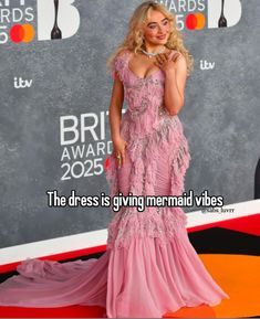 a woman in a pink dress standing on a red carpet with the caption, i am