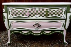 a green and pink dresser sitting on top of gravel