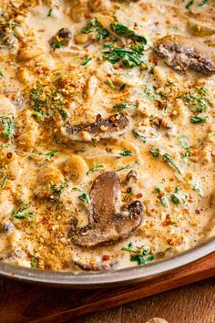 a pan filled with cheese and mushrooms on top of a wooden table