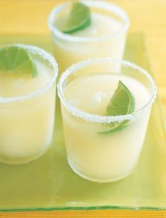 three glasses filled with drinks sitting on top of a green tray next to each other