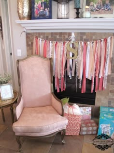 a pink chair sitting in front of a fireplace next to a shelf with clothes on it