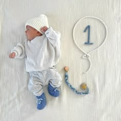 a baby laying on top of a white blanket next to a number 1 sign and headband