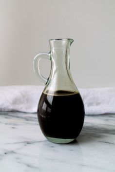 a glass bottle filled with liquid sitting on top of a marble counter next to a white towel