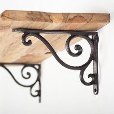 a wooden shelf with wrought iron brackets on it