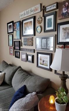 a living room with pictures on the wall and a lamp in front of the couch