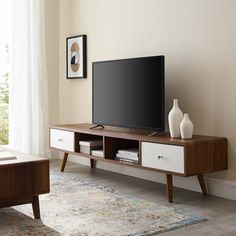 a flat screen tv sitting on top of a wooden entertainment center next to a window