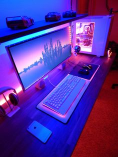 a computer desk with a keyboard, mouse and headphones on it in front of a purple light