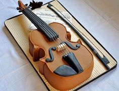 a violin cake on a sheet with music notes and leaves around the base, as well as an instrument