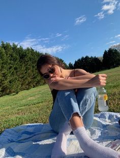 a woman sitting on top of a blanket next to a bottle