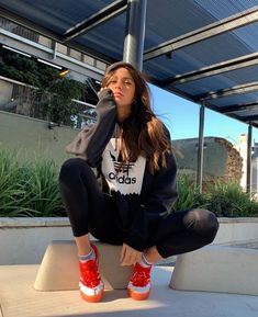 a woman sitting on top of a cement block with her feet up in the air